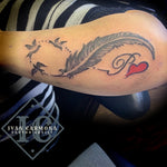 Feather And Bird Tattoo In The Shape Of The Infinity Symbol With A Commemorative Initial And Red Heart On The Forearm Tatuaje De Pluma Y Pájaro En Forma De Símbolo De Infinito Con Una Inicial Conmemorativa Y Un Corazón Rojo En El Antebrazo<br>